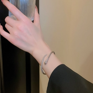 Detail van een zilveren slangvormige open armband met diamant-inleg en schubbentextuur
