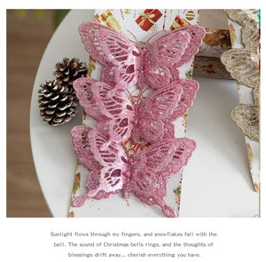 Three pink glitter butterfly ornaments for Christmas tree decor on white table with pine cones