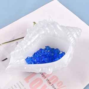 Detail van schelpvormige opbergdoos van hars met glinsterende afwerking en blauwe kristallen