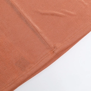 Detailed close-up of burnt orange ribbed knit fabric with neat stitching and texture