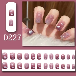 Detail of pink gradient press-on nails with white cloud patterns and glitter accents