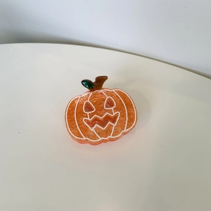Halloween pumpkin hair claw clip in orange resin with white details and green leaves