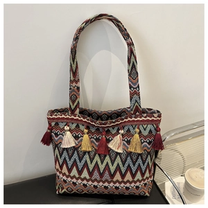 Close-up of bohemian woven tote bag with chevron patterns and colorful tassel details