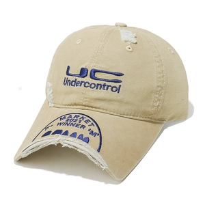 Detail of distressed beige cotton baseball cap with blue embroidery and vintage frayed brim