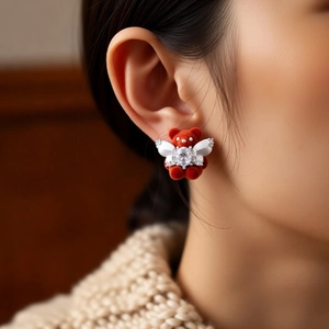 Close-up of red flocked teddy bear earrings with white bow and sparkling zircon stone