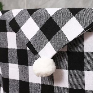 Detail of Christmas buffalo plaid chair cover featuring white pom-pom and woven texture