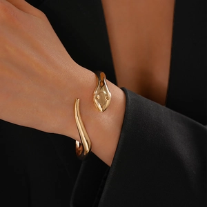 Detailed view of a gold snake-shaped bangle with a polished mirror finish on model