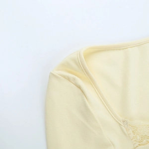 Détail d'un haut en maille côtelée jaune avec dentelle délicate sur l'encolure
