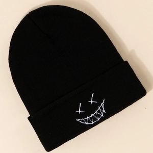 Macro detail of high-quality knit texture and white embroidered spooky face on black beanie