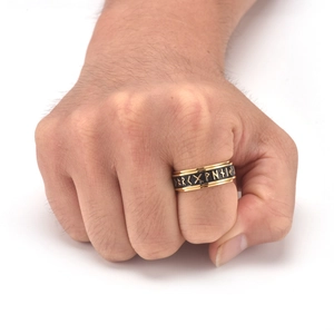 Macro detail of Nordic rune spinning ring with gold edges and black enamel finish