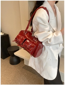Détail du sac en cuir verni bordeaux avec nœuds décoratifs et poches avant pratiques