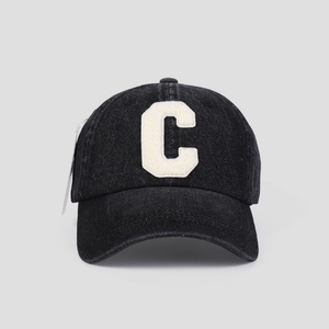 Close-up of black washed denim baseball cap featuring white bouclé embroidered letter C logo