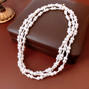 Close-up of multi-layer white pearl necklace with gold clasp on a luxury leather box