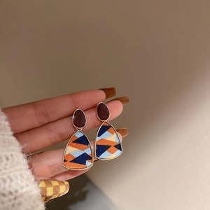Close-up of vintage geometric earrings with oval studs and multicolor triangle dangles