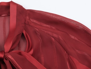 Detail of dark red chiffon blouse featuring satin stripes and an elegant neck tie bow