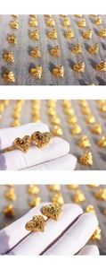 Macro detail of gold heart earrings with lava texture and zircon inlay in a studio shot