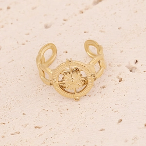Dettaglio macro anello dorato con stella bussola e fascia a catena su pietra