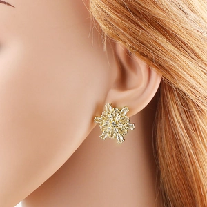 Pendientes de copo de nieve chapados en oro con circonitas brillantes en la oreja