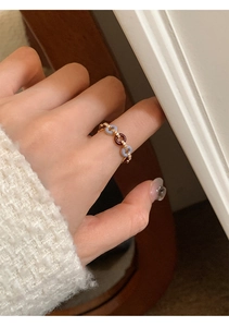 Detailed close-up of a gold chain ring with blue and brown enamel and small crystals