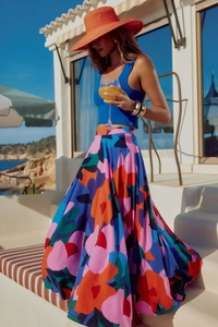 Dettaglio di gonna midi bohémien a fiori con top blu vibrante e cappello di paglia chic