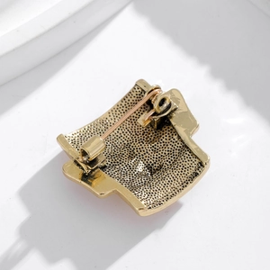 Detailed back view of Sanxingdui mask brooch showing the pin clasp and textured metal