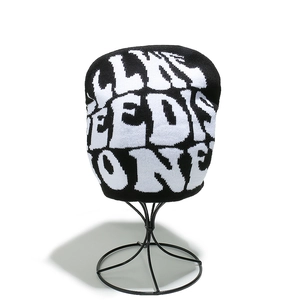 Detail of the chunky knit beanie showing the black and white LIVE NEEDS ONE jacquard pattern