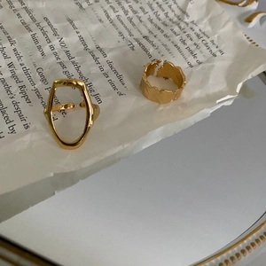 Detailed macro view of gold textured wide ring and oval hollow ring on vintage paper