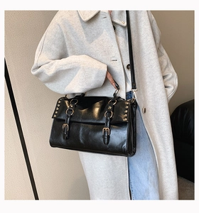 Detail of vintage black satchel with double buckle straps and metallic rivets on leather