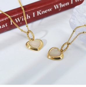 Detailed shot of gold heart pendant necklaces with white shell inlay on a book background