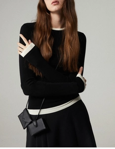 Close-up of black wool knit set featuring contrast white trim and mini leather bags