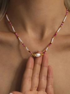Dettaglio di una collana di perline rosa e bianche con ciondolo di perla su modella
