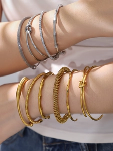 Detail of stacked gold and silver stainless steel bangles with diverse textured designs