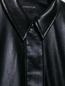 Detailed close-up of a black faux leather jacket featuring the collar and grain texture