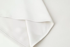 Macro detail of high-quality stitching and white satin fabric texture on the dress hem