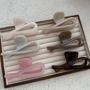 Detailed top view of large hair claws in six colors displayed on a beige jewelry tray