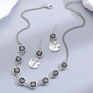 Detail of luxury necklace and earrings set with grey crystals and textured metal disks