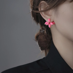 Detailed close-up of a pink floral petal earring with gold trim worn by a model