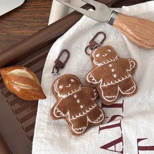Close-up of cute plush gingerbread man keychains with white embroidery on linen