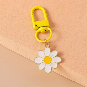 Detail of yellow D-shaped metal hook and white daisy charm on a stylish keychain