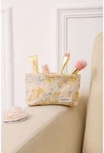 Broderie détaillée de fleurs jaunes sur une trousse de maquillage en coton et lin