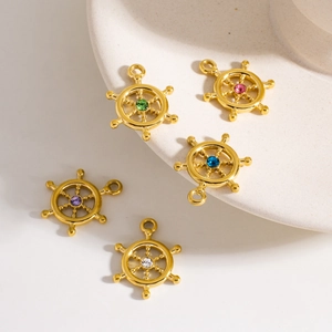 Set of five vintage gold rudder pendants with colorful inset crystals on a ceramic plate