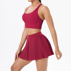 Detail view of red tennis set showing a high-waisted pleated skirt and racerback sports bra
