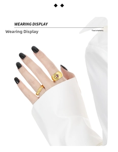 Detail of layered gold texture rings with purple stone on model hand against white shirt