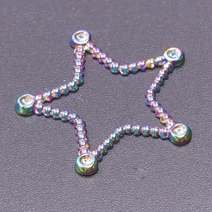 Macro shot of 18k gold plated rainbow star charm with bead texture and tiny zircon inlay