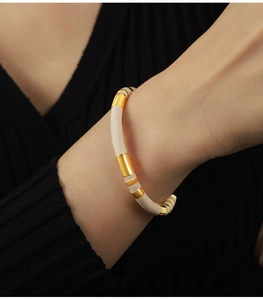 Close-up of minimalist gold titanium bangle with cream enamel inlay on a female wrist