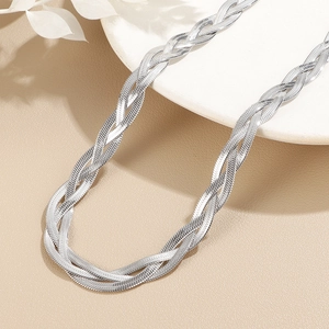 Detailed macro view of a multi-layer silver braided snake chain necklace on beige background