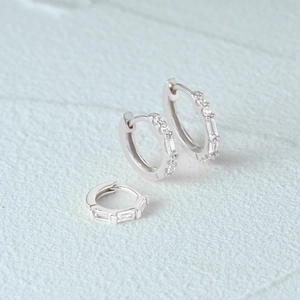 Macro view of silver 925 hoops featuring square and round white cubic zirconia stones