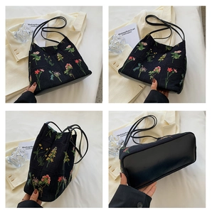 Detailed close-up of colorful floral embroidery on a black canvas bucket bag