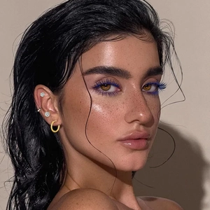 Close-up of a gold hoop earring and three silver sparkling stud earrings on a model