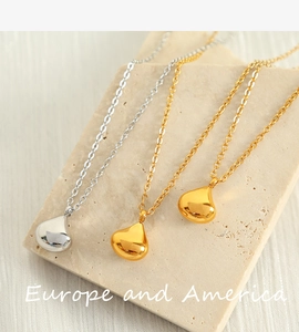 Macro shot of minimalist gold and silver water drop pendants on stone surface
